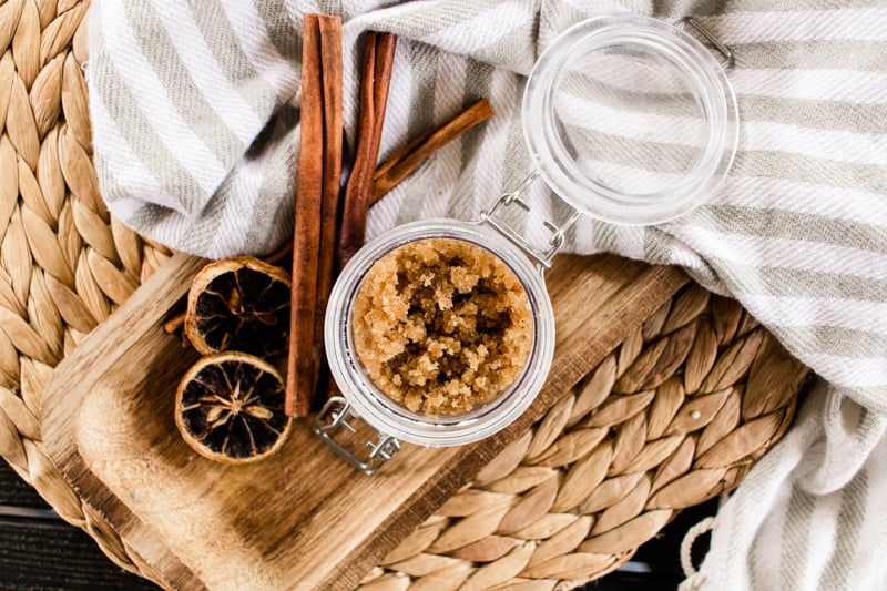 Top down view of fall body scrubs with orange slices and cinnamon sticks. 