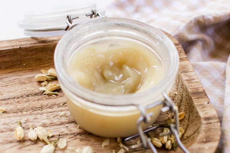 A jar of curl enhancing cream on a wooden tray. 