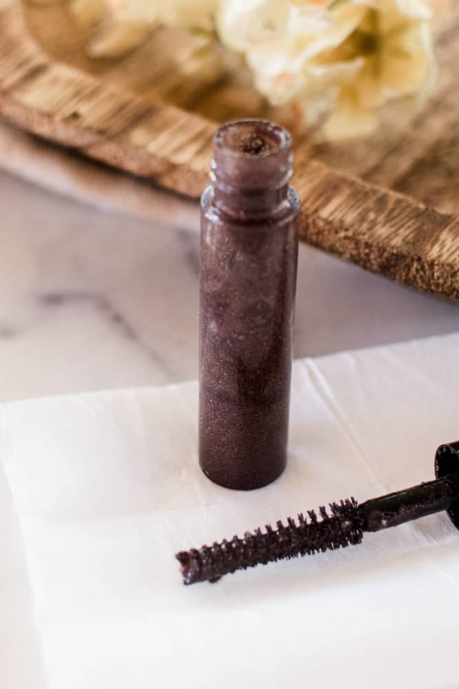 A close up jar of DIY eyebrow gel and brush. 