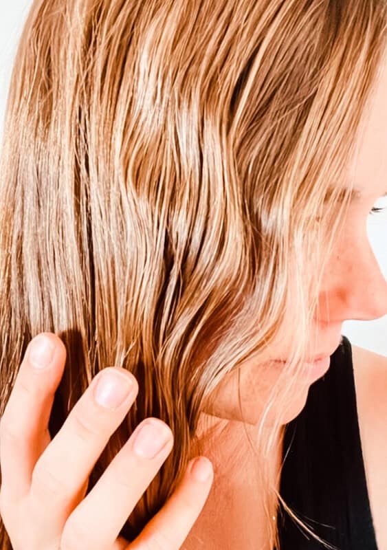 Running hands through wavy hair after applying homemade curl cream.
