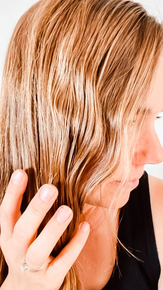 Running hands through wavy hair after applying homemade curl cream.