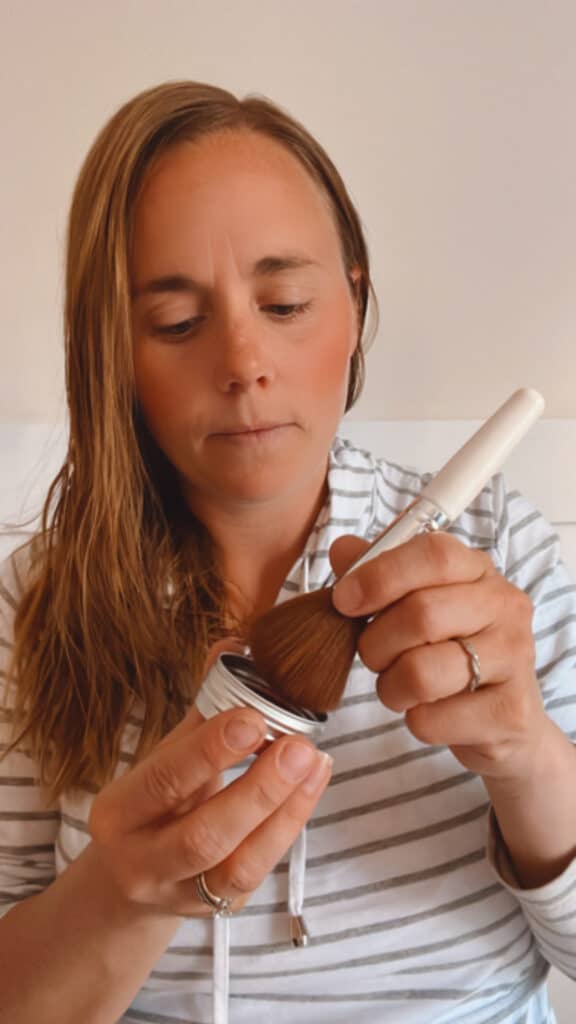 Applying homemade blush with a small applicator.