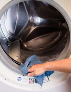 Wiping down the front seal of a washing machine.