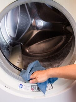 Wiping down the front seal of a washing machine.