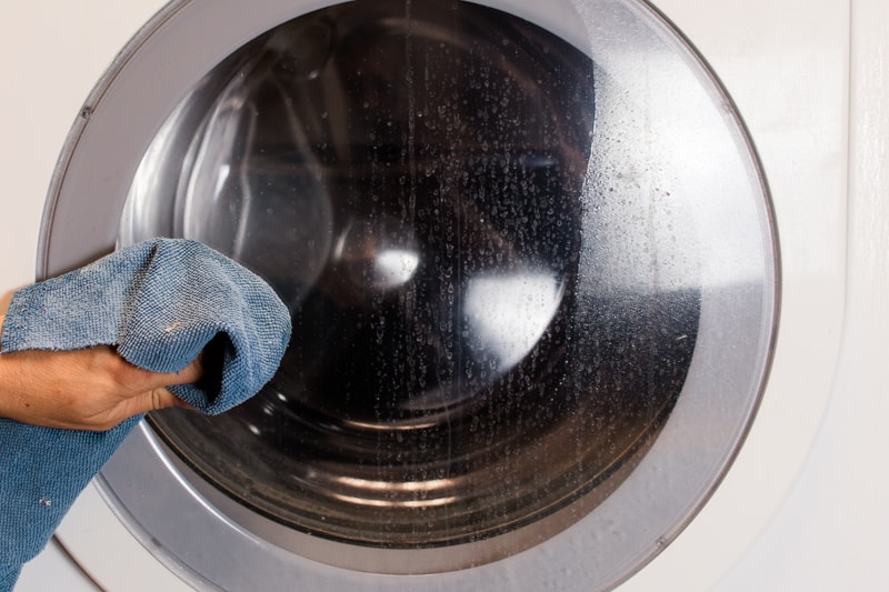Cleaning the washer door with a microfiber cloth. 