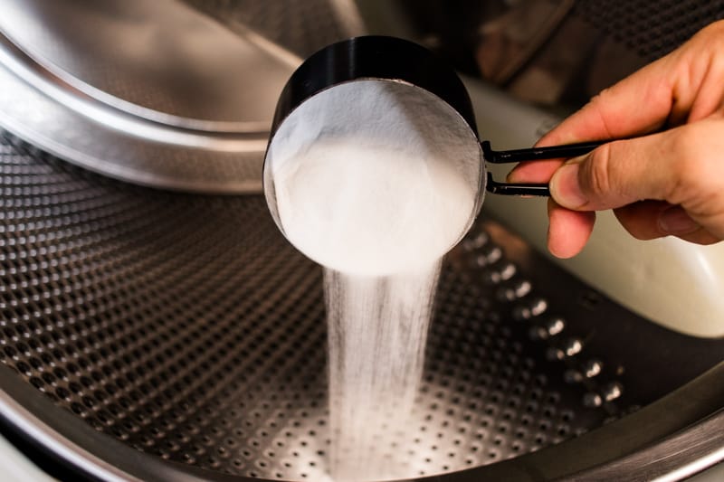 Adding baking soda to the washer drum. 