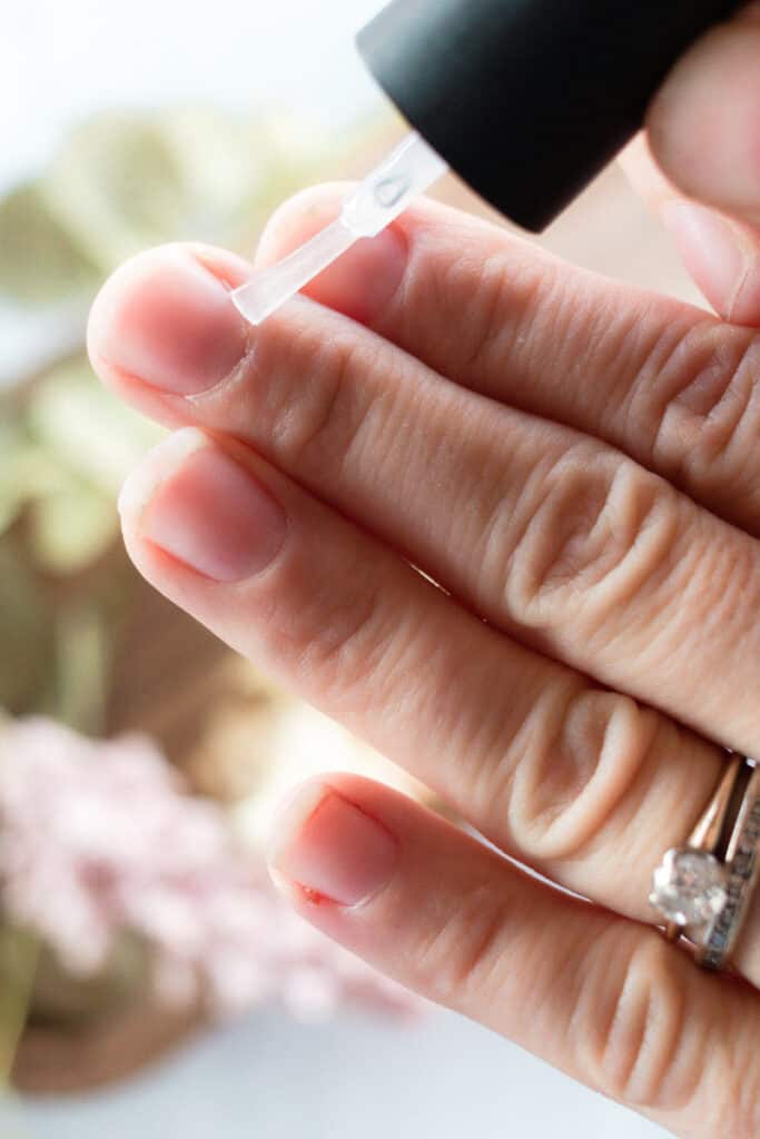 Applying cuticle oil to cuticles. 