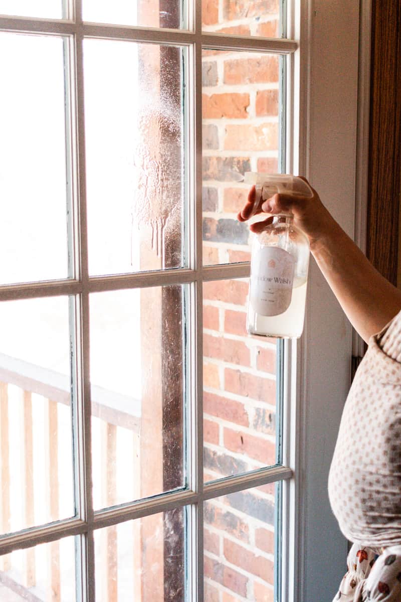 A homemade vinegar cleaning solution being sprayed onto window panes. 