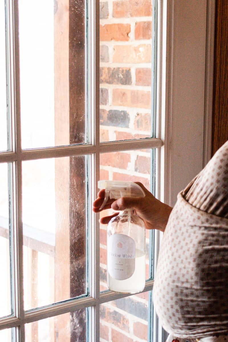 Spraying windows with a homemade cleaning solution. 