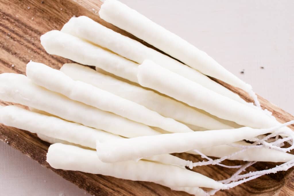 A bunch of hand dipped tapered candles on a drying board.