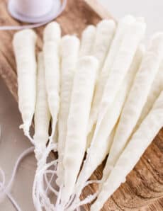 Hand dipped candles made from soy wax hardening on a wooden slab.