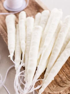 Hand dipped candles made from soy wax hardening on a wooden slab.