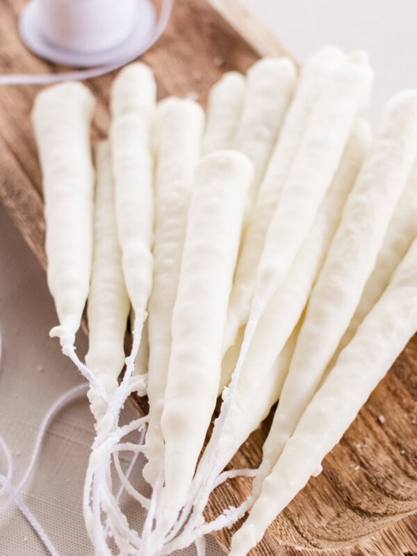 Hand dipped candles made from soy wax hardening on a wooden slab.