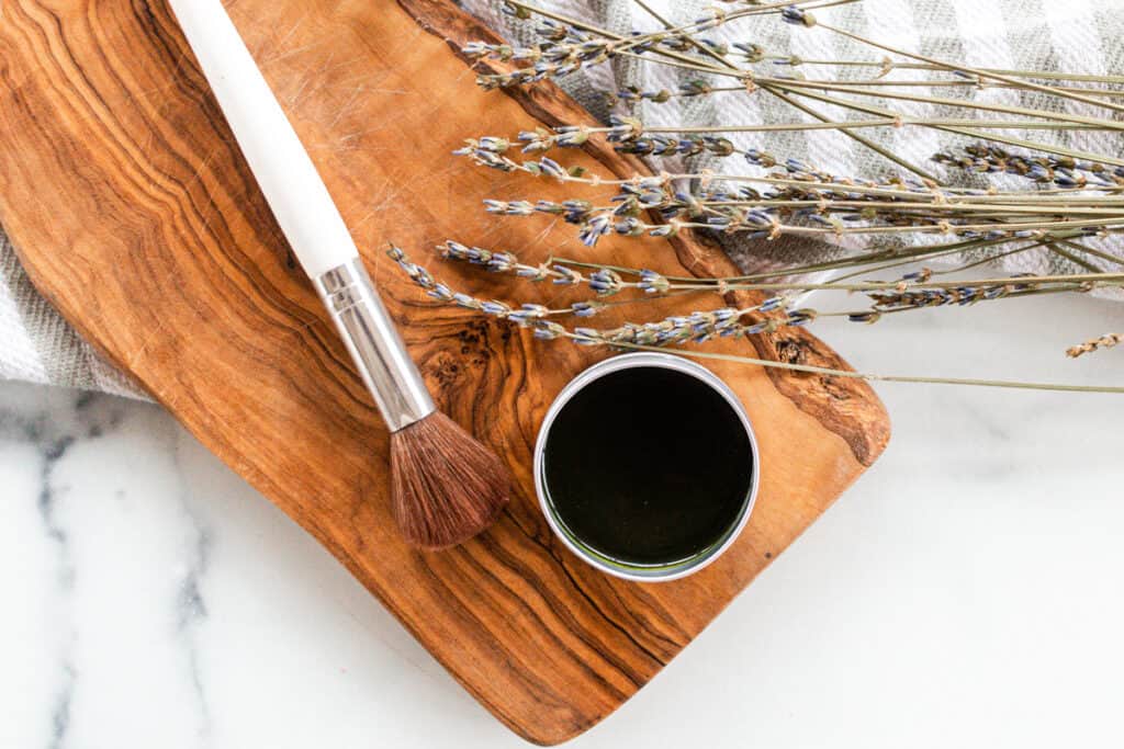 Matcha face mask and make up brush on a wooden board. 