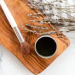 Matcha face mask brush with a tin of matcha mask paste on a marble vanity.