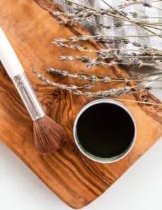 Matcha face mask brush with a tin of matcha mask paste on a marble vanity.