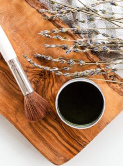Matcha face mask brush with a tin of matcha mask paste on a marble vanity.