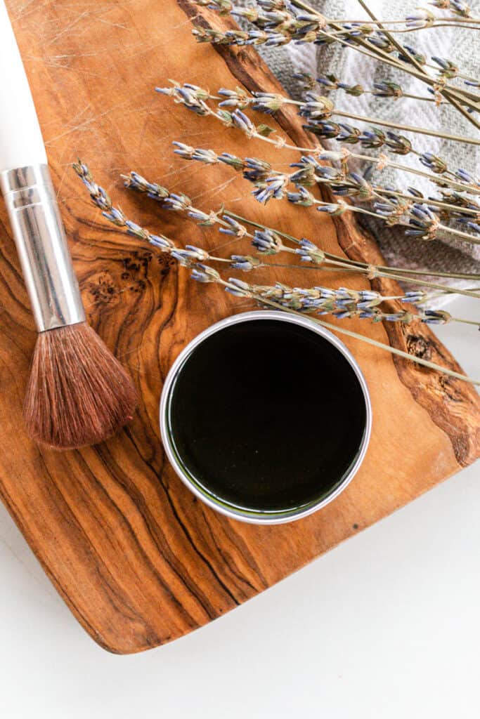 Matcha face mask in a metal tin with make up brush alongside. 