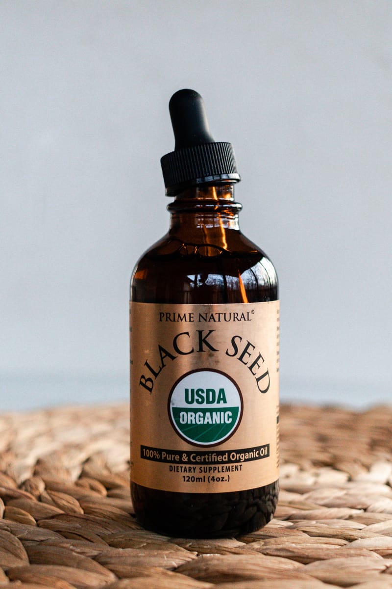 A bottle of black seed oil for hair on a wicker mat. 