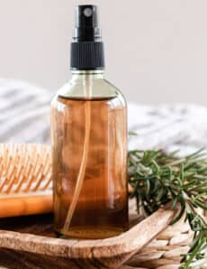 Homemade rosemary water for hair in a glass spray bottle.
