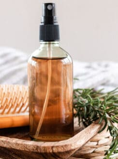 Homemade rosemary water for hair in a glass spray bottle.