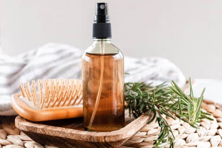Homemade rosemary water for hair in a glass spray bottle.
