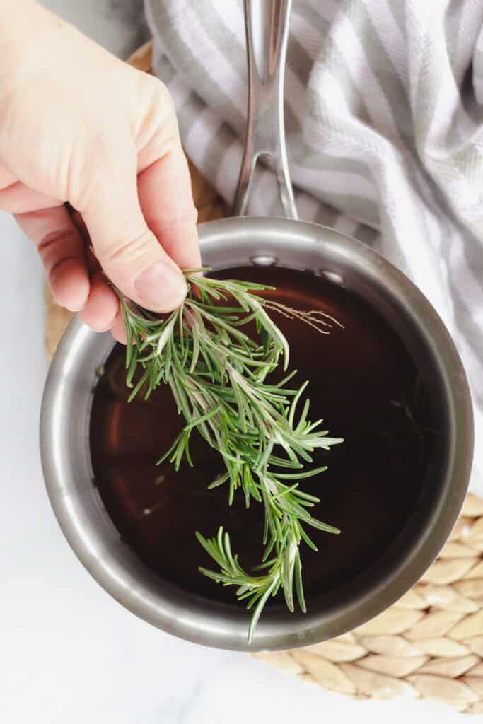 Rosemary sprigs being placed into water. 