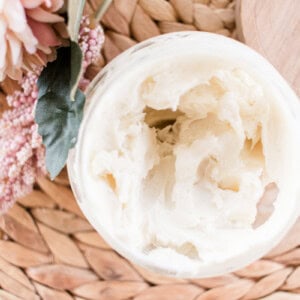 Natural body cream in a open top glass storage jar.