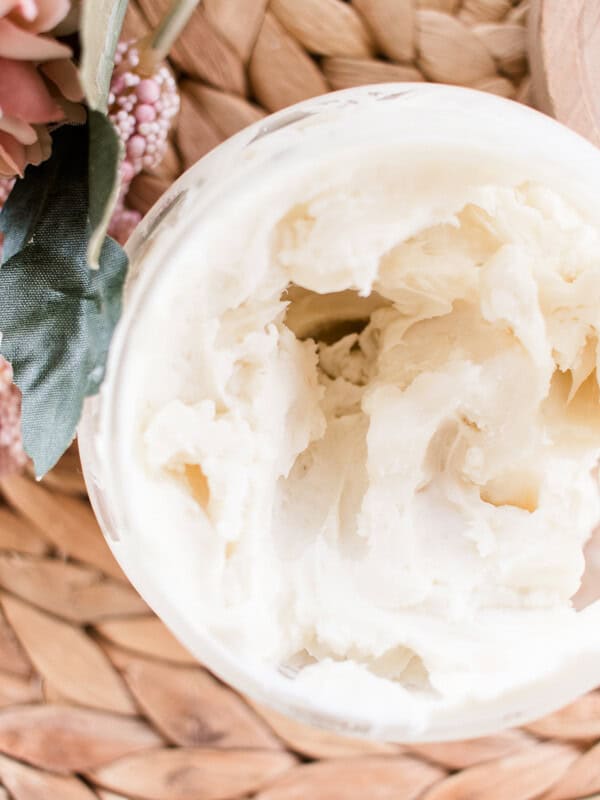 Natural body cream in a open top glass storage jar.
