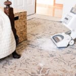 Vacuuming up baking soda from the carpet to get rid of cat urine odor.