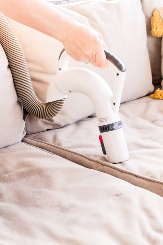 Vacuuming upholstery with a homemade cleaner.