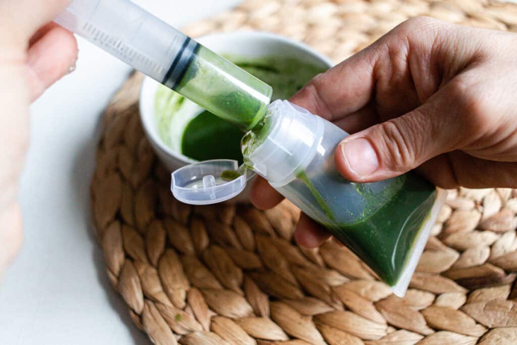 Filling a squeeze tube with gel face cleanser using a transfer tube.