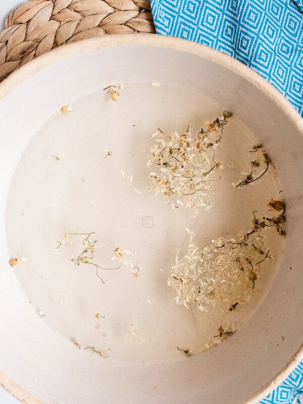 Odor fighting foot soak with dried chamomile flowers in a large bowl.