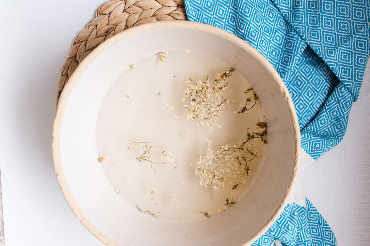 Odor fighting foot soak with dried chamomile flowers in a large bowl.