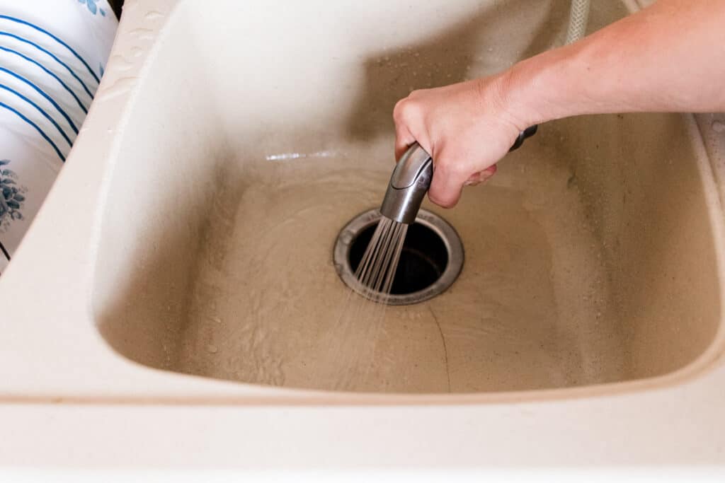 Rinsing the homemade sink cleaning solution out with warm water.