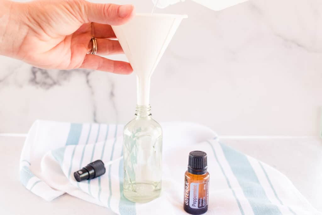 A funnel, glass bottle and peppermint oil. 