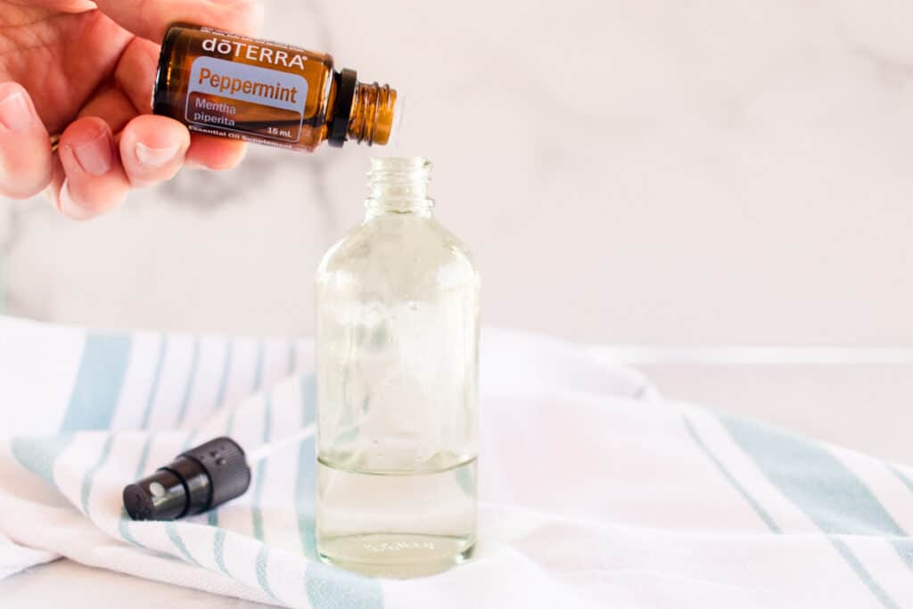 Adding peppermint oil to a glass bottle of mouse repellent. 