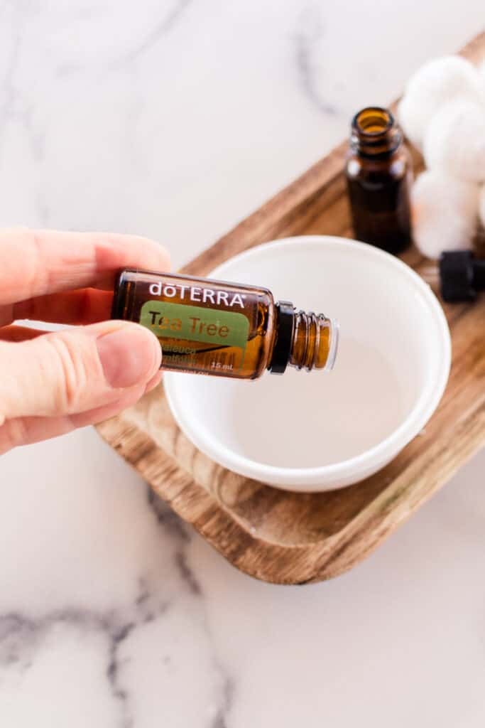 Adding tea tree oil to a white bowl. 