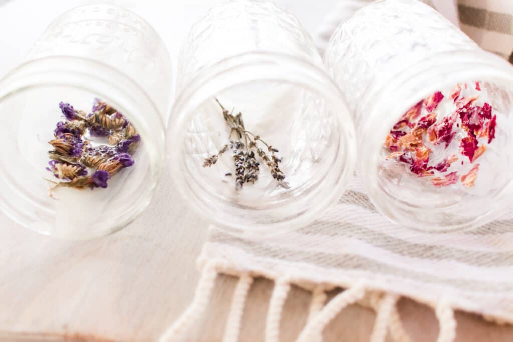 Mason jar candles with dried flowers pressed up against the side and being held with a touch of wax.