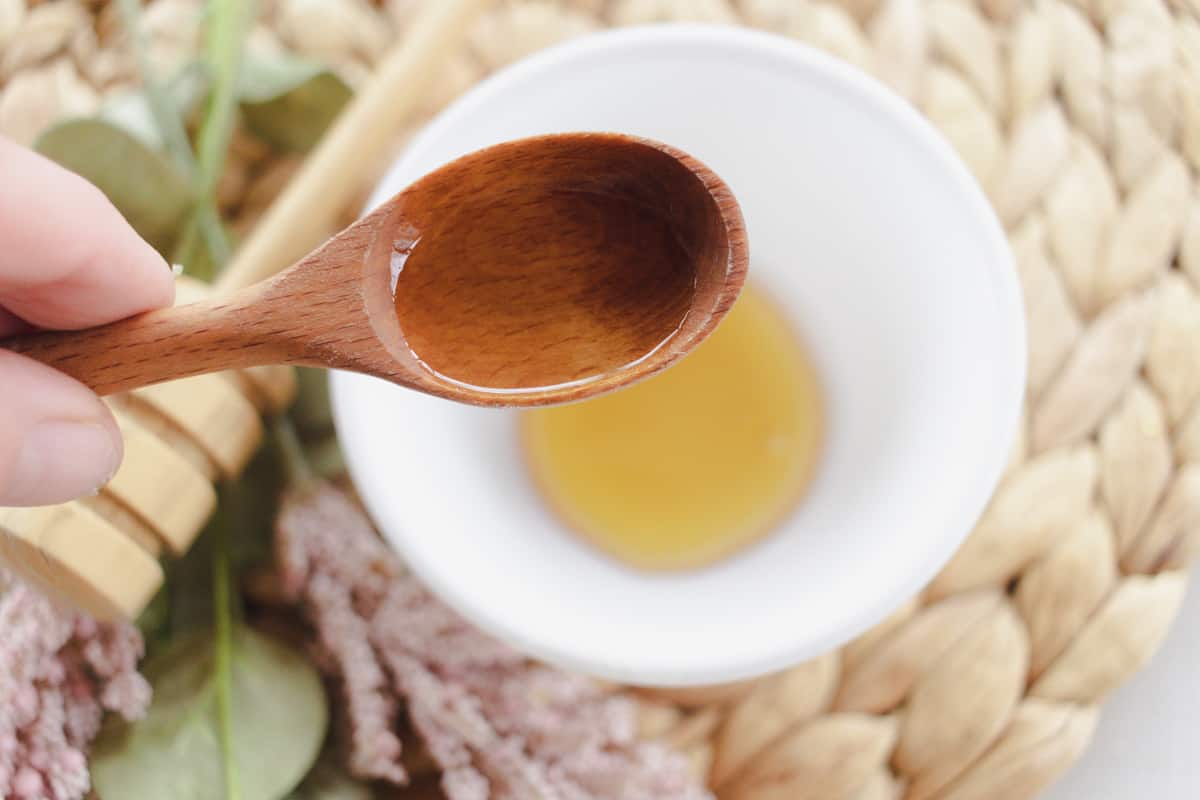 Using a wooden spoon to add almond oil to the under eye mask.