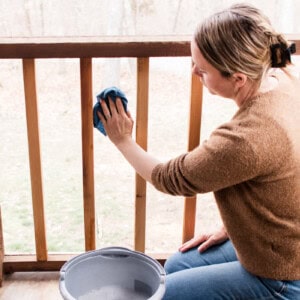 Cleaning a porch screen with warm soapy water and a microfiber cloth.