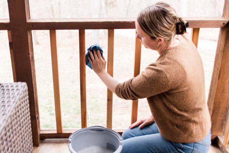 Cleaning a porch screen with warm soapy water and a microfiber cloth.