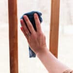 Scrubbing down a porch screen with dish soap and a wet cloth.