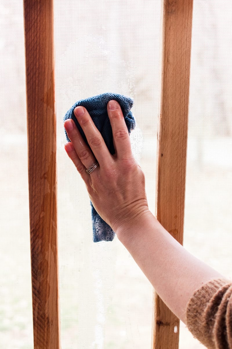 Soaping off the porch screen with a microfiber cloth.