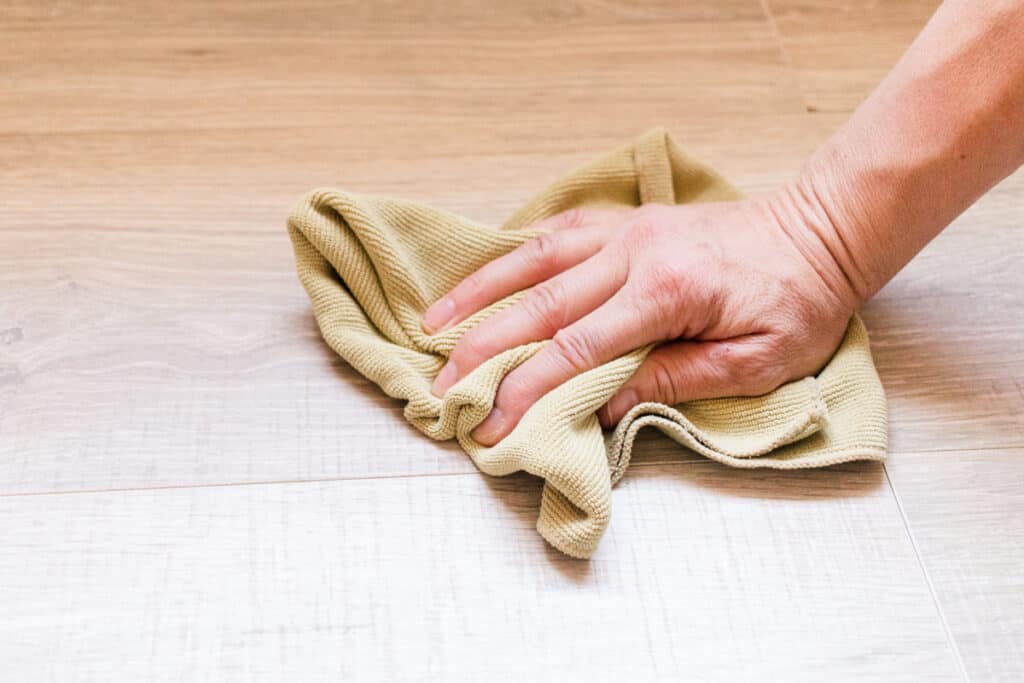 Buffing laminate flooring in a circular motion.