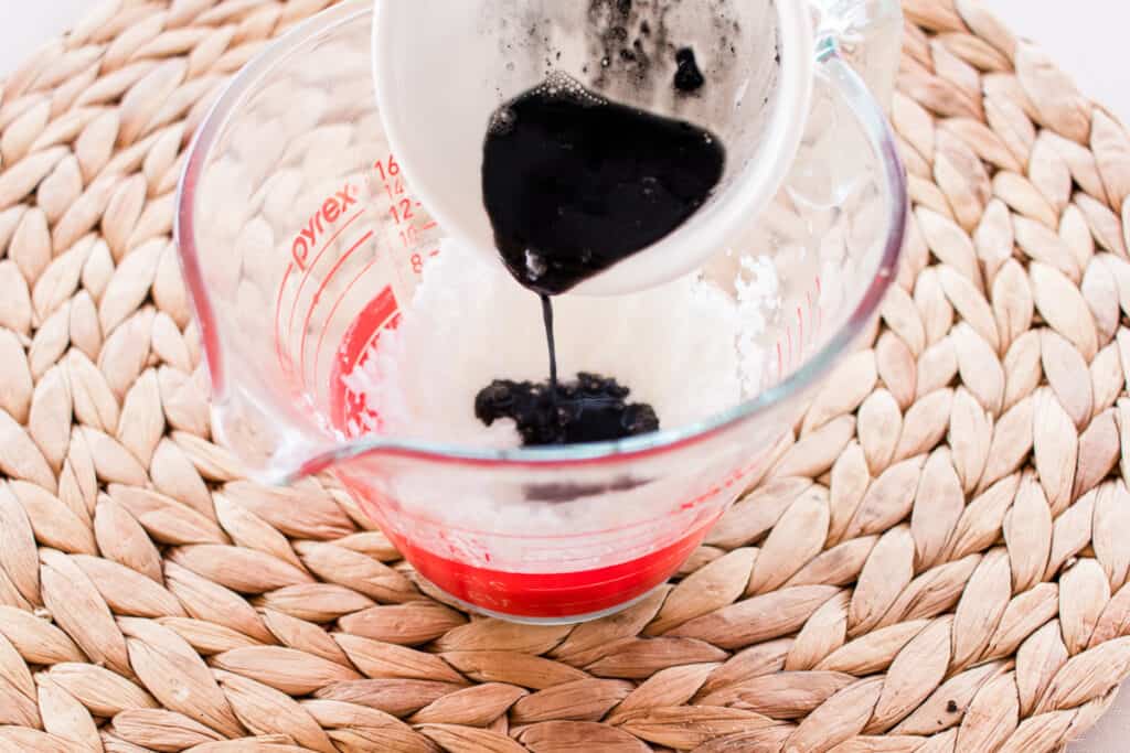 Adding charcoal powder to a mixing jug. 