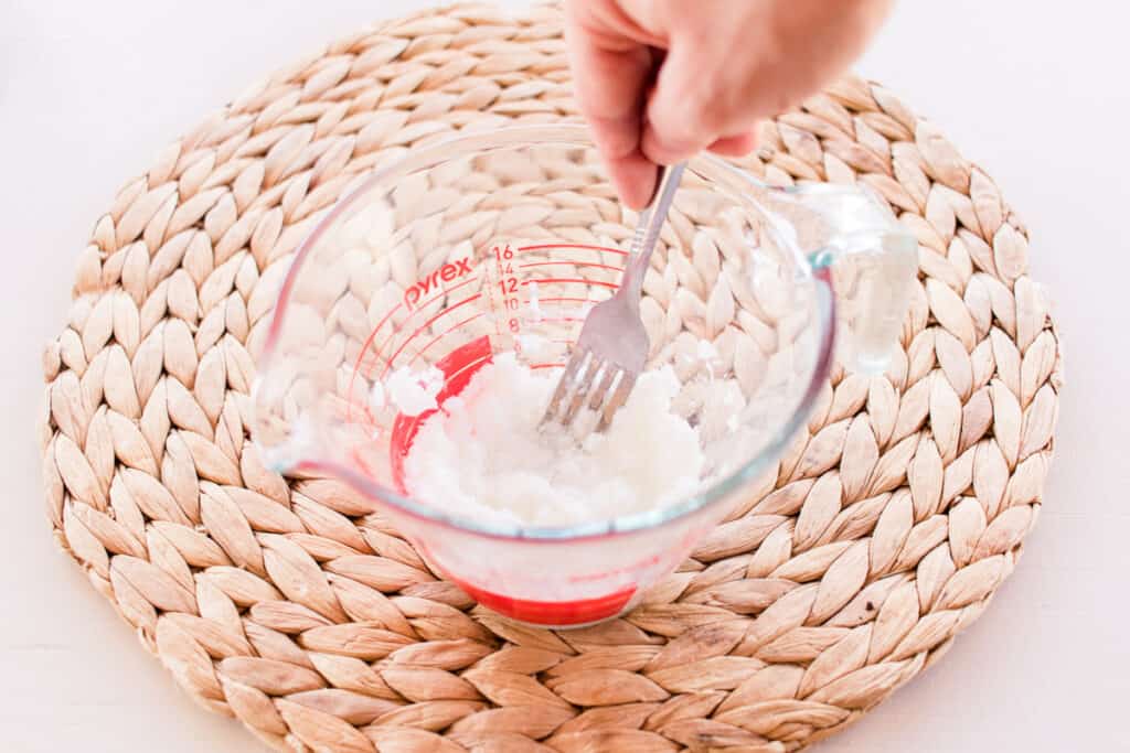 Using a fork to combine castile soap and the salt water.