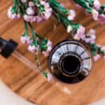 Glass jar of cleansing oil on a wooden tray.