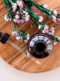 Glass jar of cleansing oil on a wooden tray.