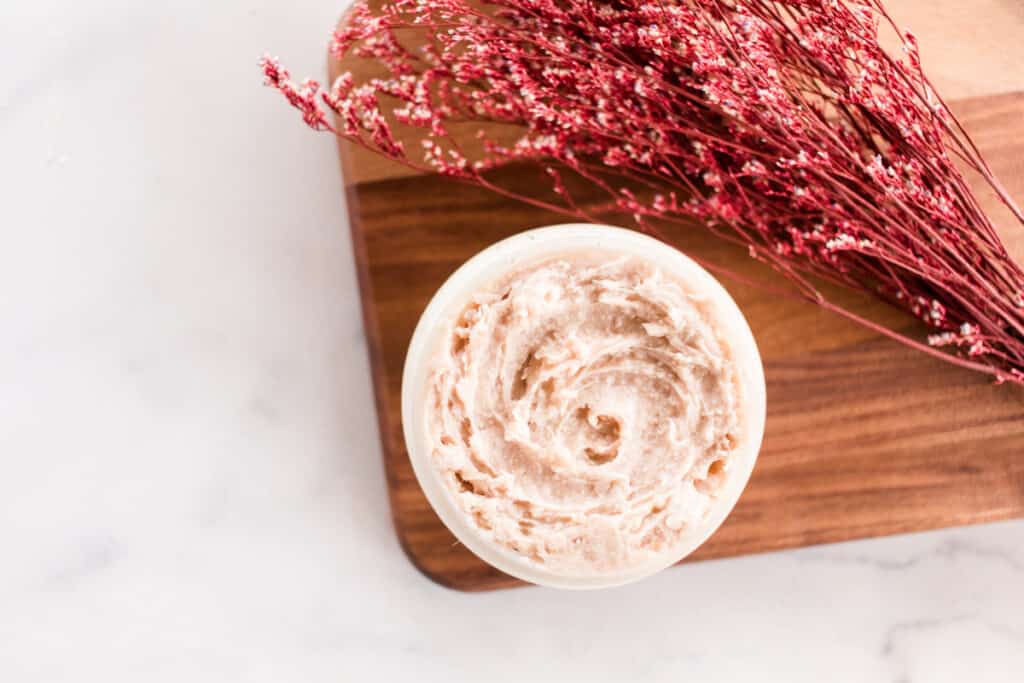 Tinted moisturizer with red flowers on a wooden cutting board.